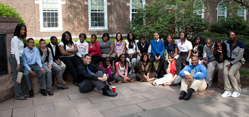 A group of students pose for a group picture in two long rows in front of a brick building.
