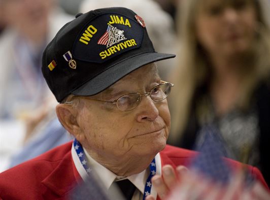 World War II veteran looking off into the distance, wearing a hat that says "Iwo Jima"