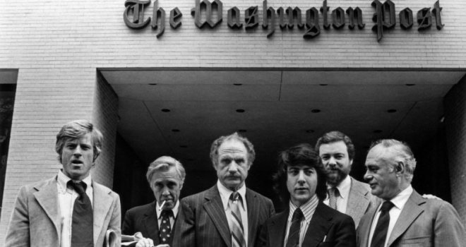 Six men, including Robert Redford and Dustin Hoffman, standing in front of The Washington Post building during filming of All the President's Men.