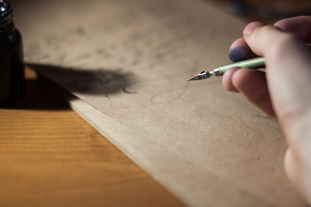 A person writing a letter with an old fashioned pen. Writing a letter about a current and controversial issue is a great method for teaching civics.