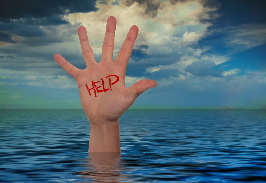 A hand sticking out of the ocean with "help" written on it.