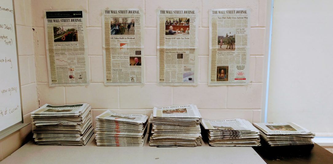 Five days of the Wall Street Journal laid out on a desk in a classroom